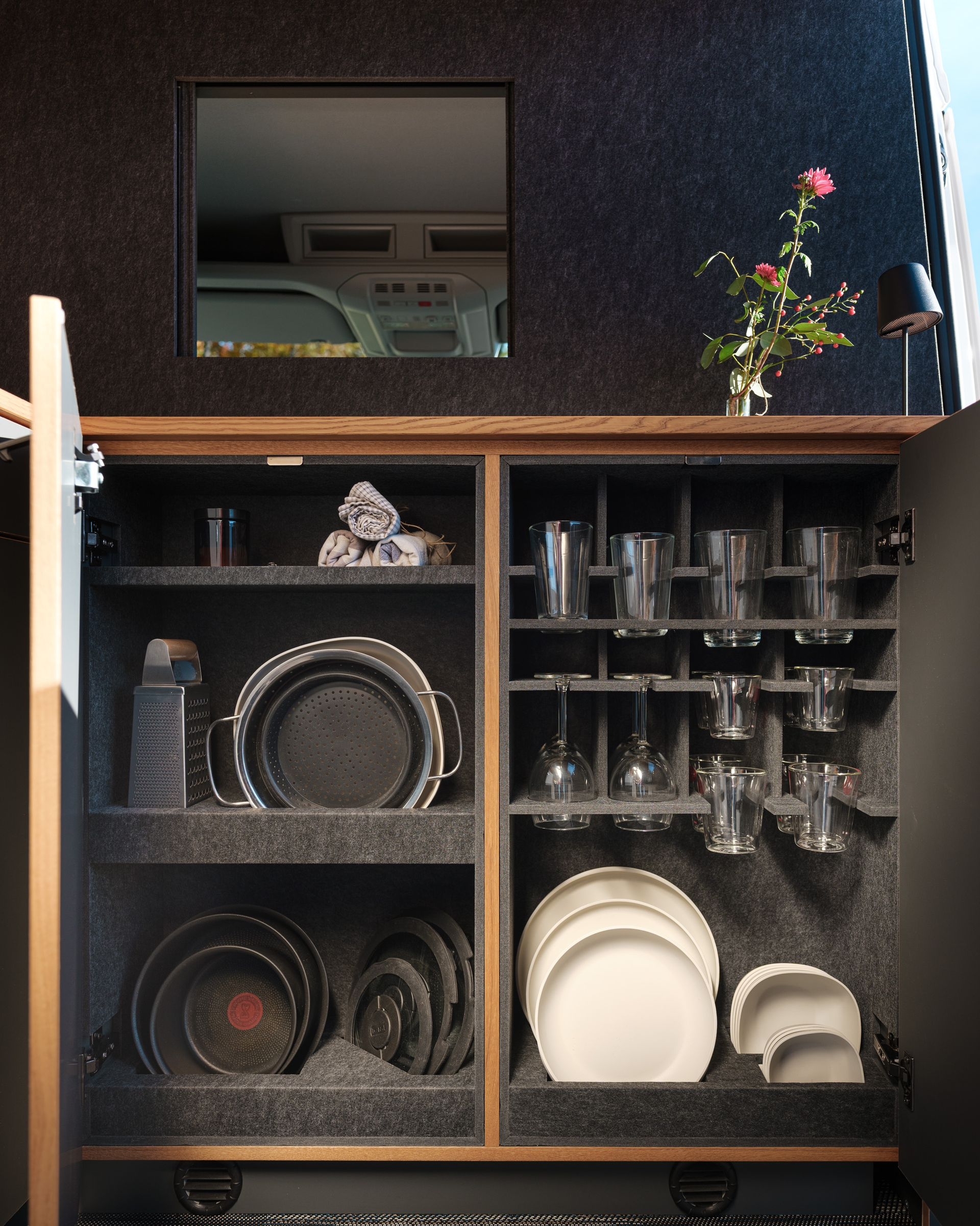 Vollausgerüstete Küche im Camper Van Patgific von Cocoon Vans. Die Möbel sind mit robustem Filz ausgestattet, die Halterungen für Gläser und Teller sind aus dem Filz geschnitten, so das alles an seinem Platz bleibt.